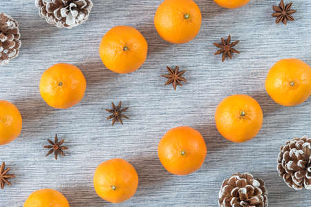 Diagonal rows of oranges, star anise, and pinecones on grey backgroundの写真素材