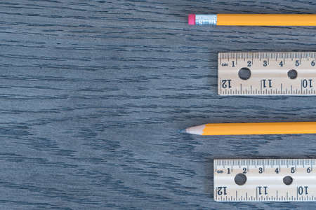 Flat lay of pencils and wood rulers on wood grain backgroundの写真素材