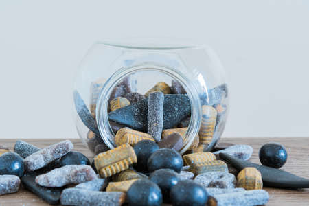 Salmiakki spilling out of open candy jar and onto tableの写真素材