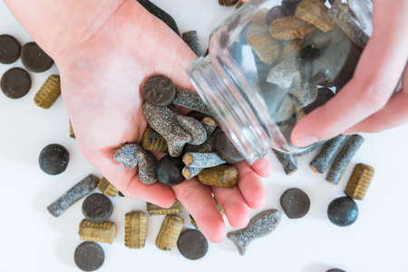 Assorted double salted liquorice being poured from candy jar into womans hand