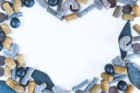 Different varieties of salmiakki arranged in heart-shaped frame on solid white backgroundの写真素材