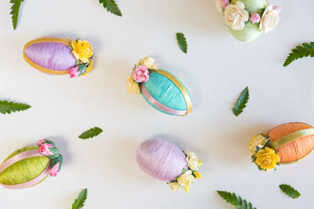 Easter eggs and small green leaves arranged on white background