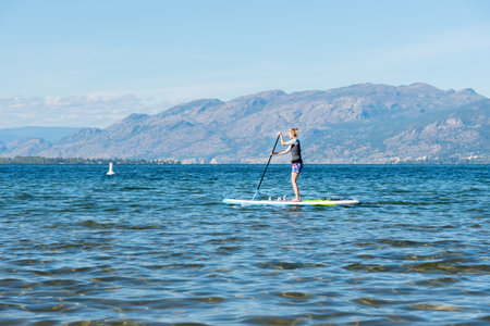 Penticton, British Columbia/Canada - September 21, 2019: a woman  uses a stand-up paddle-board on...