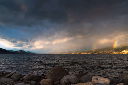 View of dramatic storm clouds and double rainbows over Okanagan Lake, BC, Canadaの写真素材