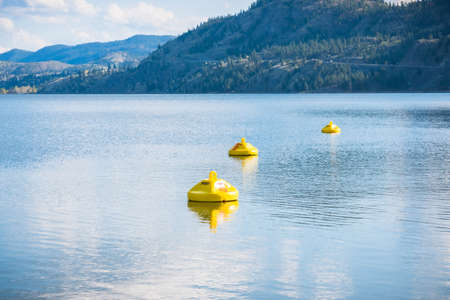 Yellow buoys marking hazardous area with dangerous under currents on lake, where swimming is not permittedの写真素材