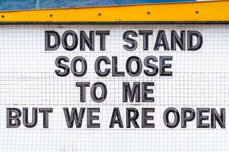 Humorous social distancing sign outside open business during coronavirus pandemicの写真素材