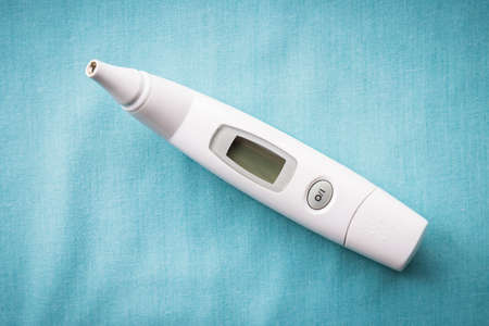 Close-up of digital ear thermometer on sold blue background with copy spaceの写真素材