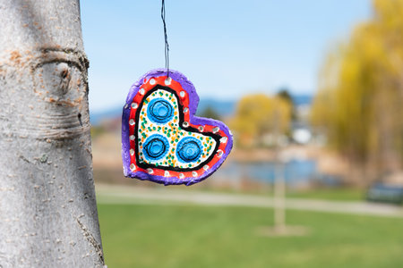 Penticton, British Columbia/Canada - April 16, 2020: a handmade heart hangs from a tree in Skaha Park. Hearts have become a symbol of hope and solidarity during the coronavirus pandemic.のeditorial素材