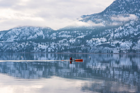 Penticton, British Columbia/Canada - December 28, 2020: a person paddles a kayak across Skaha Lake during the calm after a winter storm. The lake is often free of ice for most of winter.のeditorial素材