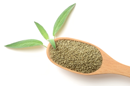 dried sage powder in the wooden spoon, isolated on white, top viewの写真素材