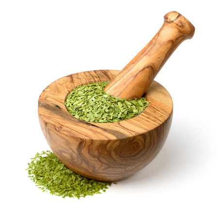 dried tarragon leaves in the wooden mortar, isolated on whiteの写真素材