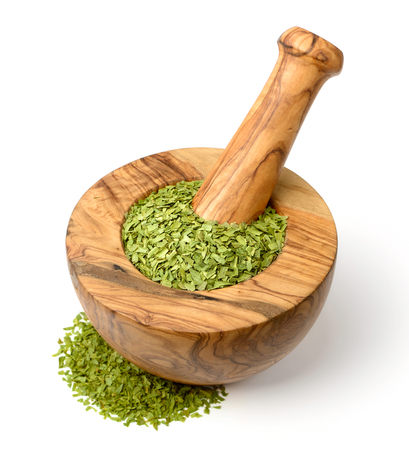 dried tarragon leaves in the wooden mortar, isolated on whiteの写真素材