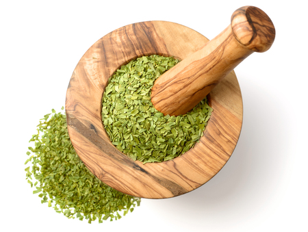 dried tarragon leaves in the wooden mortar, isolated on whiteの写真素材