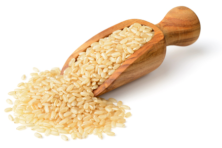 raw brown rice in the wooden scoop, isolated on the white backgroundの写真素材