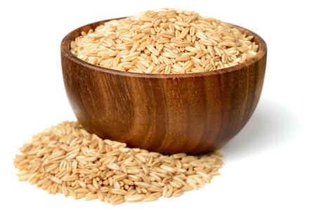 uncooked oats in the wooden bowl, isolated on whiteの写真素材