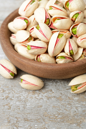 pistachio nuts with shell in the wooden plateの写真素材