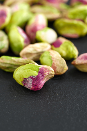 peeled pistachios on the black stone boardの写真素材