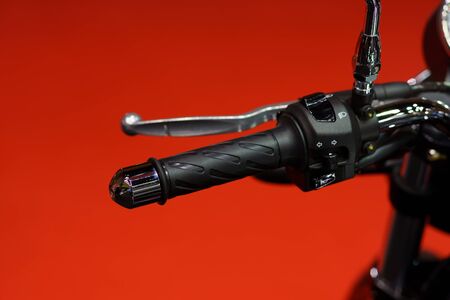 Motorcycle handle bar. Close up of motorcycle left handle bar on red background;の写真素材