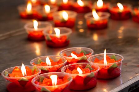 Many burning red flower candles cup at chinese templeの写真素材