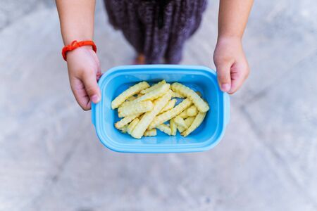 Golden French Fries Potatoes in a plastic cup on kid hand.の写真素材