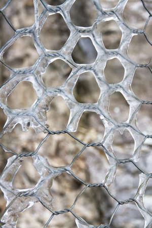 Closeup of a wire-mesh fence covered in frozen water and ice