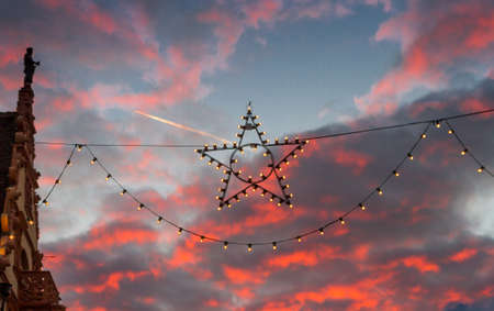 Christmas Star in front of pink dusk clouds at the Christmas market in Colmar, Franceの写真素材