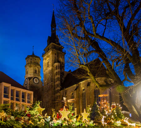 The main Stuttgart medieval parish church \"Stiftskirche\" inside the Christmas market during blue hourの写真素材