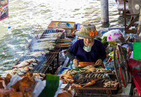 Bangkok, Thailand - November 2, 2013 - Thai woman grills sea food in a boat at Taling Chan Floating Market in Bangkok in November 2013.のeditorial素材