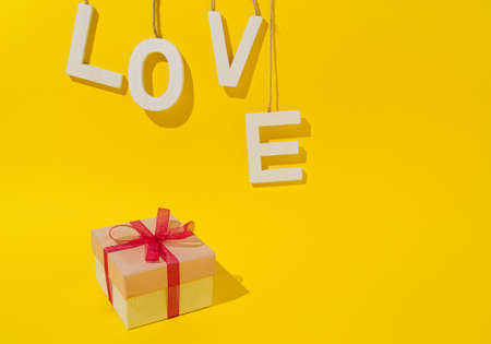 Realistic pink gifts box with white word love,for Valentine's day or birthday,on the yellow background wit space for text.の写真素材