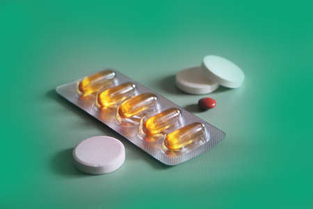 Pharmaceuticals pills medicine honey color capsules and white pills on green backgroundの写真素材