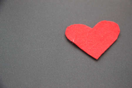 Red felt heart on dark brown background. Love concept.の写真素材