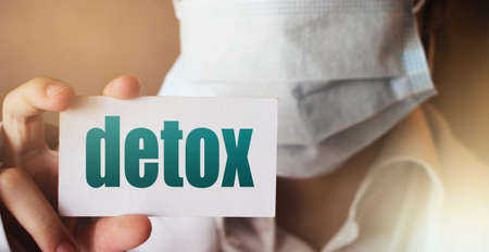Doctor holding a card with DETOX, Medical rehabilitation get rid of addiction concept.の写真素材