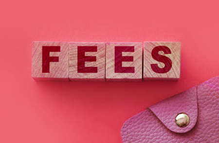 Fees word on Wooden cubes and pink wallet. Small Business startup concept.