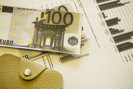 Banknotes of 100 euros on financial graphs chart and leather wallet. Money, financial growth success concept.の写真素材