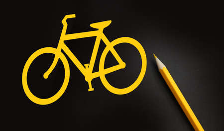 Bicycle yellow sign on black and a pencil besides. Healthy living and energy saving concept.の写真素材