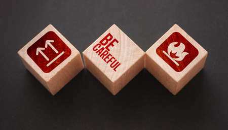 Wooden Cubes with the text: Be Carefull and icons meaning flamable and no turing upside down. Beware concept.の写真素材