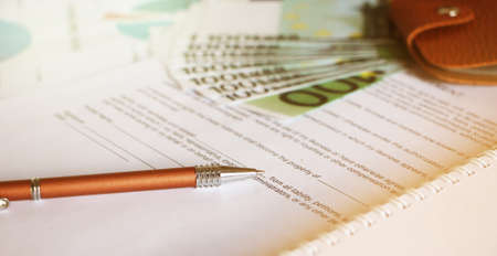 100 Euro bills leather wallet and a pen on unsigned agreement. Signing on a business form concept.