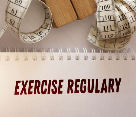 Measurement tape and Exercise regulary words on the page of copybook. Fitness traning, regular exercises, slimming and losing eight healthy eating concept.の写真素材