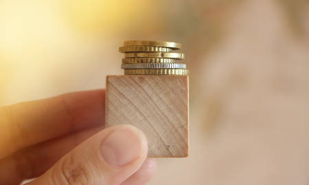 Wooden cube oins on it in the hand. Saving and investment business concept.の写真素材