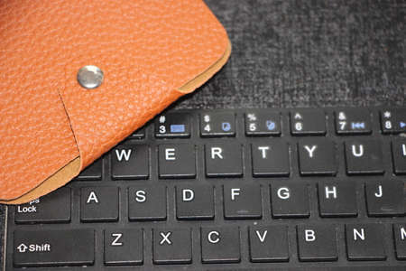 Brown leather wallet put on computer keyboard. Online business web shopping buying via internet...