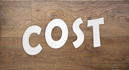 Cost word letters cut from white paper on wooden background. Cost, expense or company profit and loss business concept, analyze spending or payment.の写真素材
