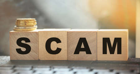 Word SCAM. Wooden small cubes with letters isolated on computer keyboards with copy space available. Concept image.の写真素材