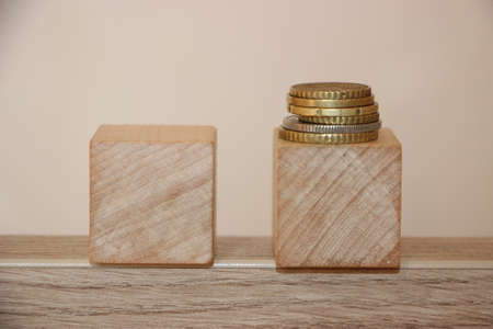 Two wooden cubes woth coins put on one cube. Desicion making concept in business or career.
