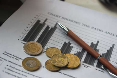 Graph chart financial report documents, euro coins and pen. Financial data analysis business concept, counting every cent and saving money concept.の写真素材