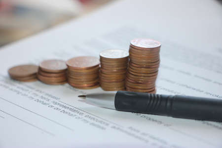 Pen and contract papers, stack of coin reminding growing diagram. Successfull business desicion making management solutions conceptの写真素材