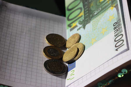 Copybook with 100 Euros bills and euro coins. Business startup concept.