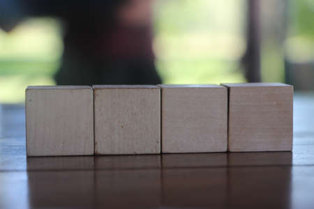 Four Wooden cubes arranged on table with copy space and nature blured background.の写真素材