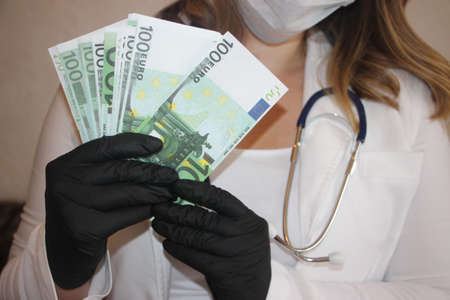 Medical services for a fee: doctor's hands counting Euro banknotes. Paid medicine business concept.の写真素材