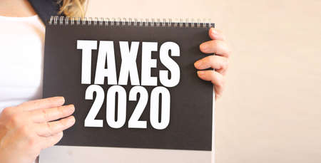 Taxe 2020 words on black notepad in businesswoman hands. Taxation and fees accounting financial...