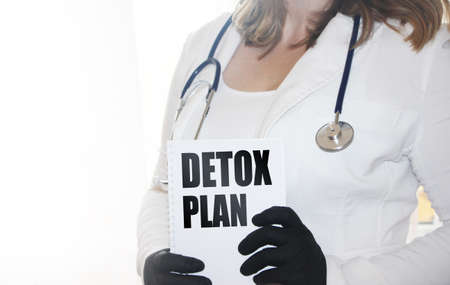 Doctor wearing white medical gown holding a notebook with text Detox plan. Healthcare concept.の写真素材